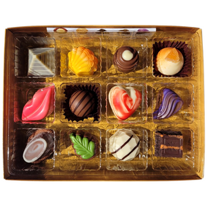 The Gift Box of 12 gourmet chocolates from Poppy's Chocolate is a premium assortment expertly arranged in three rows. These exquisite chocolates are crafted in charming shapes such as lips, hearts, and shells, showcasing vibrant colors like pink, brown, and white. Each truffle is nestled within its own compartment for a truly indulgent experience.